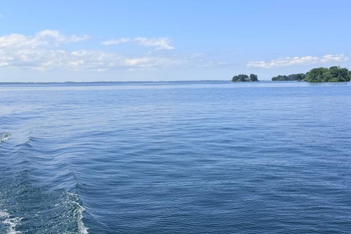 Calm blue lake with distant islands and a clear sky.