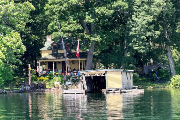House and boathouse on a lake surrounded by trees.