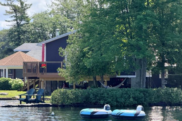 Lakeside cottage with chairs on deck and pedal boats on the water.